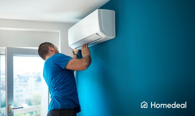 Vakspecialist is een airco aan het plaatsen tegen een blauwe muur