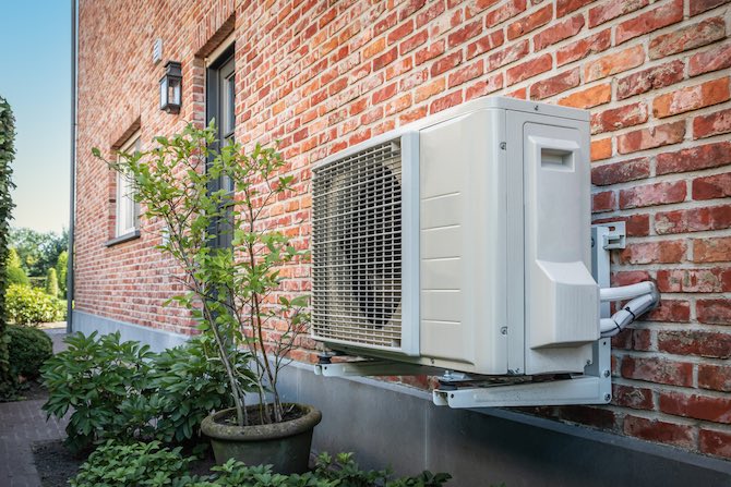 Een warmtepomp bevestigd aan de buitenmuur van de woning.