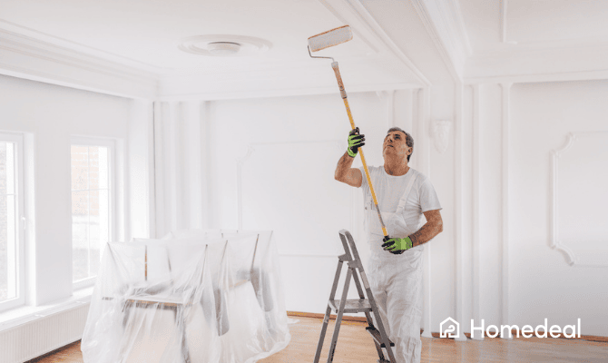 Mannelijke schilder schildert een plafond in de woonkamer